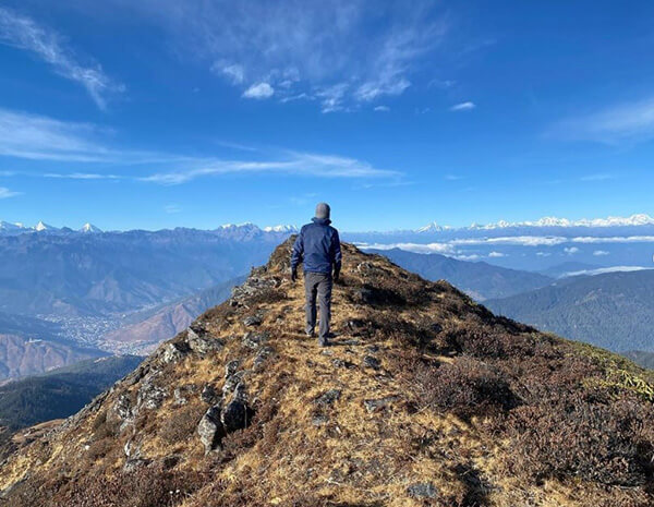 At the summit of Talakha Peak with Sir Tim, with the Himalayas in distance, and Gangkhar Puensum, the highest unclimbed peak in the world. It is forbidden to climb it.