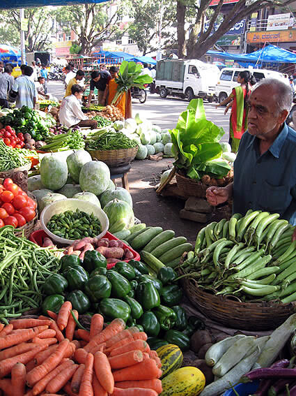 A man selling vegetables at a stand in a Bangalore market.