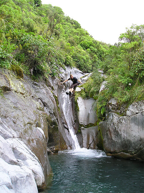 Author jumping off a waterfall in New Zealand.