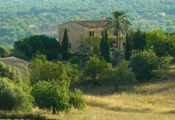 A old stone country house in southern Spain surrounded by trees and other greens.