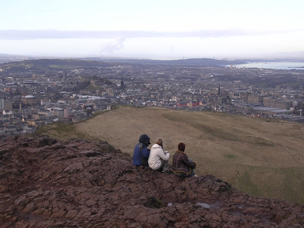 Study abroad in Scotland. Students sitting on rocks overlooking city.
