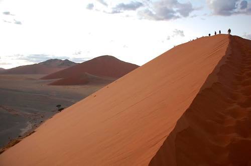 Group adventure travel climbing a sand dune in Namibia.