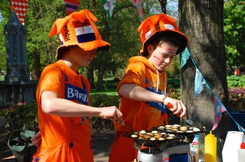 Children baking pancakes dressed in orange during the Amsterdam festival.