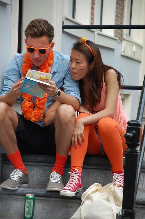 Foreigners sitting on stairs looking at map during the festival.