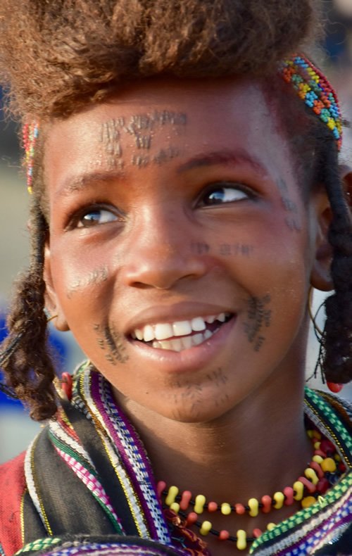 Wodaabe girl in Chad smiling with colorful beads.