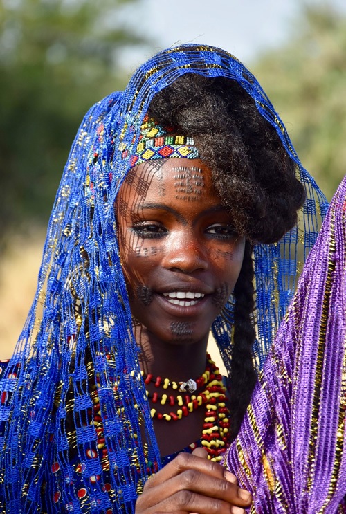 Young girl dressed in colorful headdress and beads at the festival awaiting marriage.