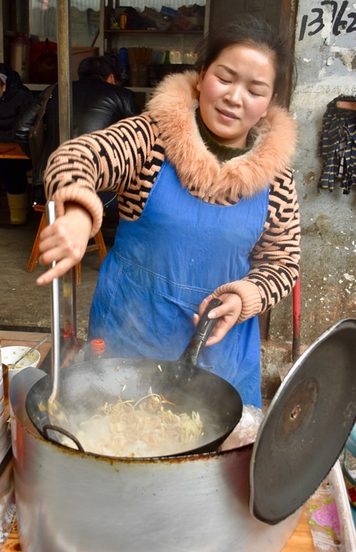 Woman cooking and serving lunch at a local market.