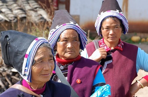 Three Bai women in hats on their way to a funeral.