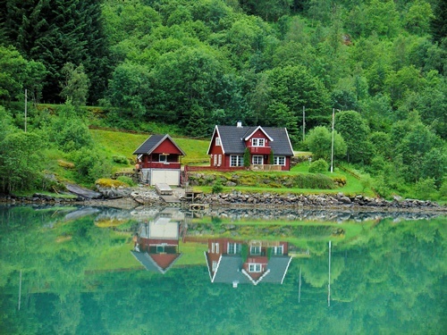 A house in the woods reflected in a lake in Fjaerland, Norway.