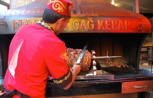 A street food vendor in Turkey is making cag kebap, slicing pieces of meat off the huge rotating spit.