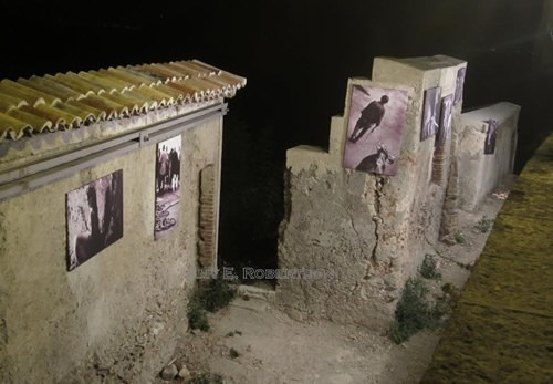Photography exhibit on old wall in Sicily.