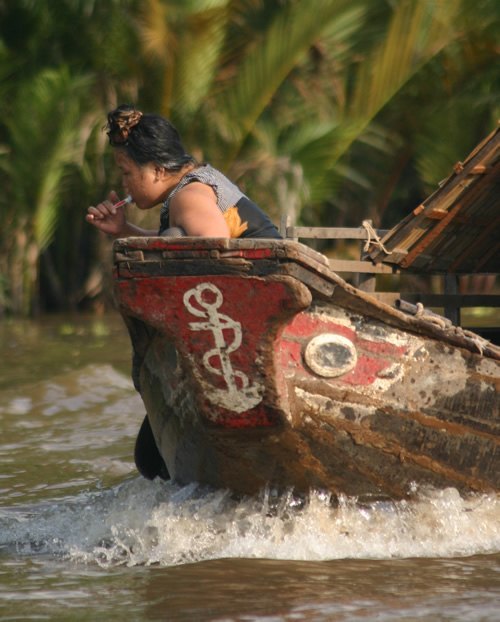 Woman brushing teeth in a boat on the Mekong river.