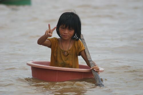 Young girl paddler floating in a tub on the Mekong River.