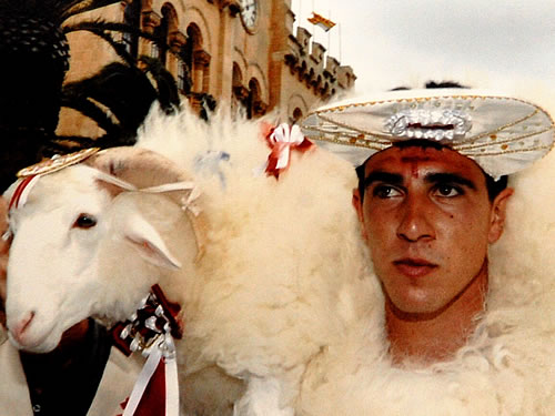 Man in white carrying a lamb during the Menorca festival.
