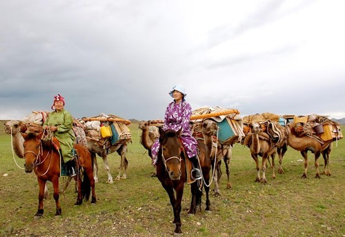 Mongolian women nomads on horseback with supplies.