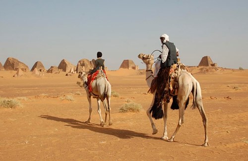 Men on camels at pyramids.
