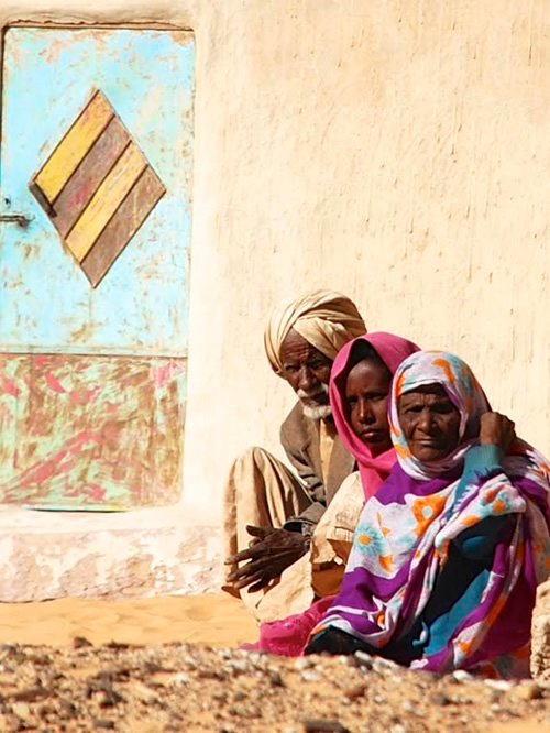 A curious family in front of their house with typical Nubian door.