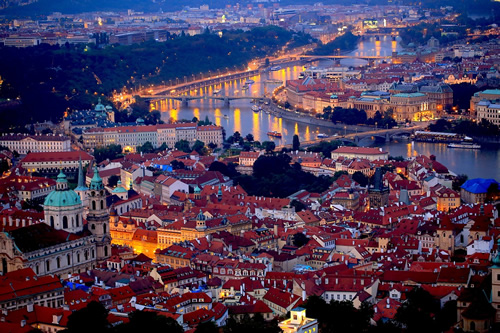 From above, Prague seen at night with the river and bridges.