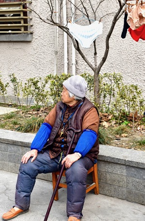 Woman sitting in Shanghai alleyway.