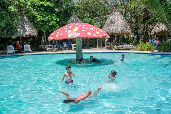Travel with children, as they enjoy swimming in a pool.