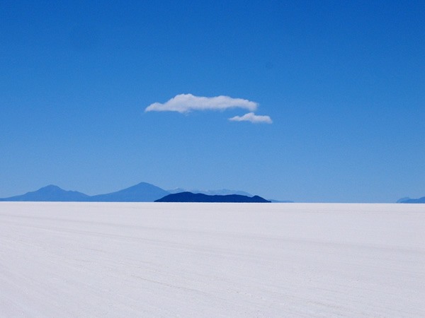 Bolivian white salt mines with hills in the background beneath blue skies.