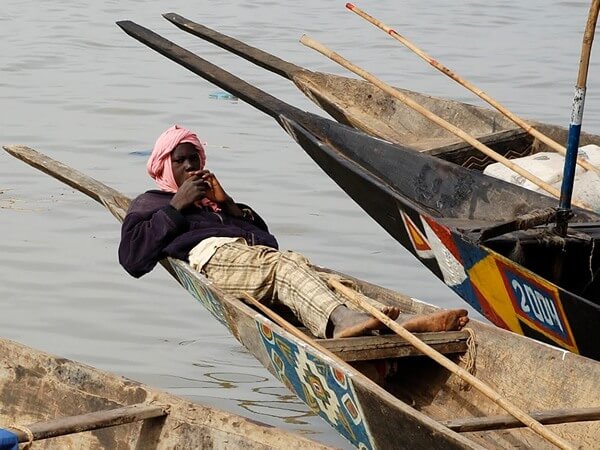 Pirogue boat in Mali with man resting on a break.