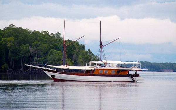 A sailboat in Indonesia near a green island.