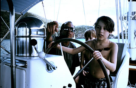 Son guiding a yacht with family.