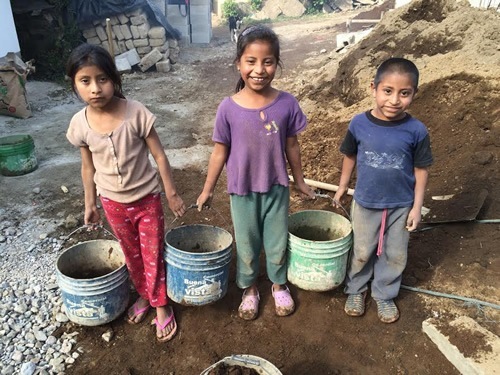 Juana, Rosa, and Fernando are moving empty buckets in a Guatemalan village.