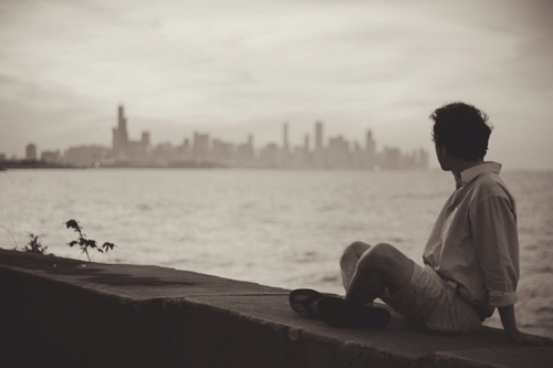 Travel writer listening to the waves and gazing at a city skyline.