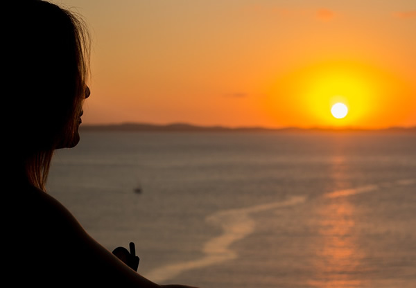 Woman traveling solo watching a sunset.