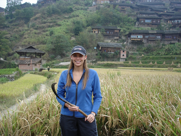 Author is an expatriate woman with a scythe in rice field in China.