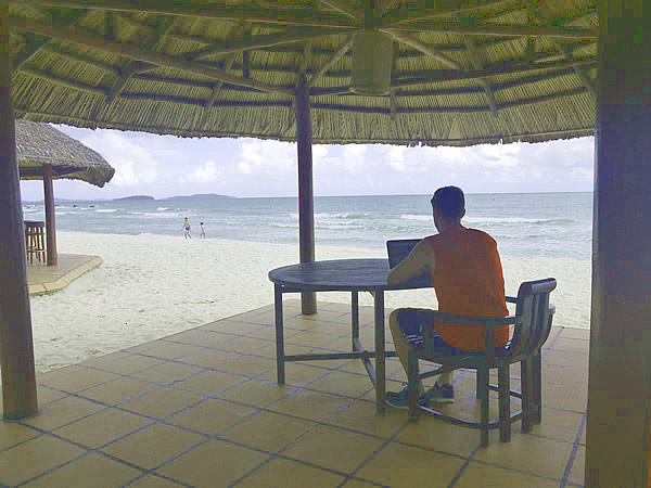 Working on web in Cambodia as a freelancer while sitting at a table by the beach.