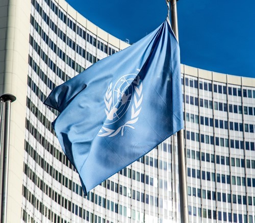 United Nations flag waving in front of UN building.