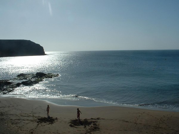 Deserted beach in Canary Islands with two walking along shore.