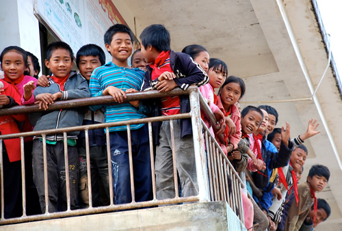 Smiling and friendly children on a school balcony waving.