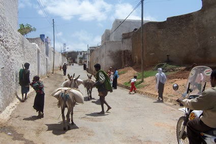 Ethiopia medieval walls in Harar, with people walking in the dirt street.