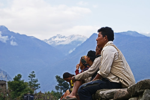 Locals sitting in Nepal in front of the mountains.