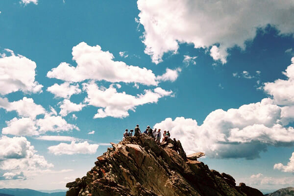 Summer teen tour with a group on top of a mountain.
