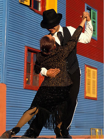 Study Abroad in Buenos Aires, Argentina. A couple dancing tango in a street in front of a colorful house.