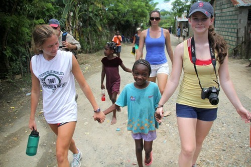 Volunteers holding hands of Dominican girl in the Dominican Republic.