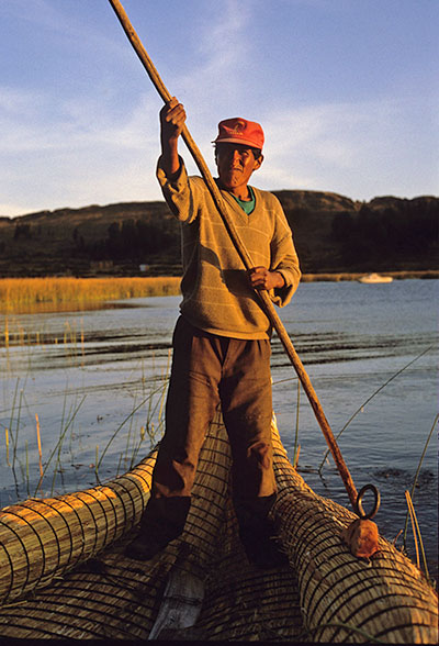 Traditional man standing rowing a boat in Bolivia.