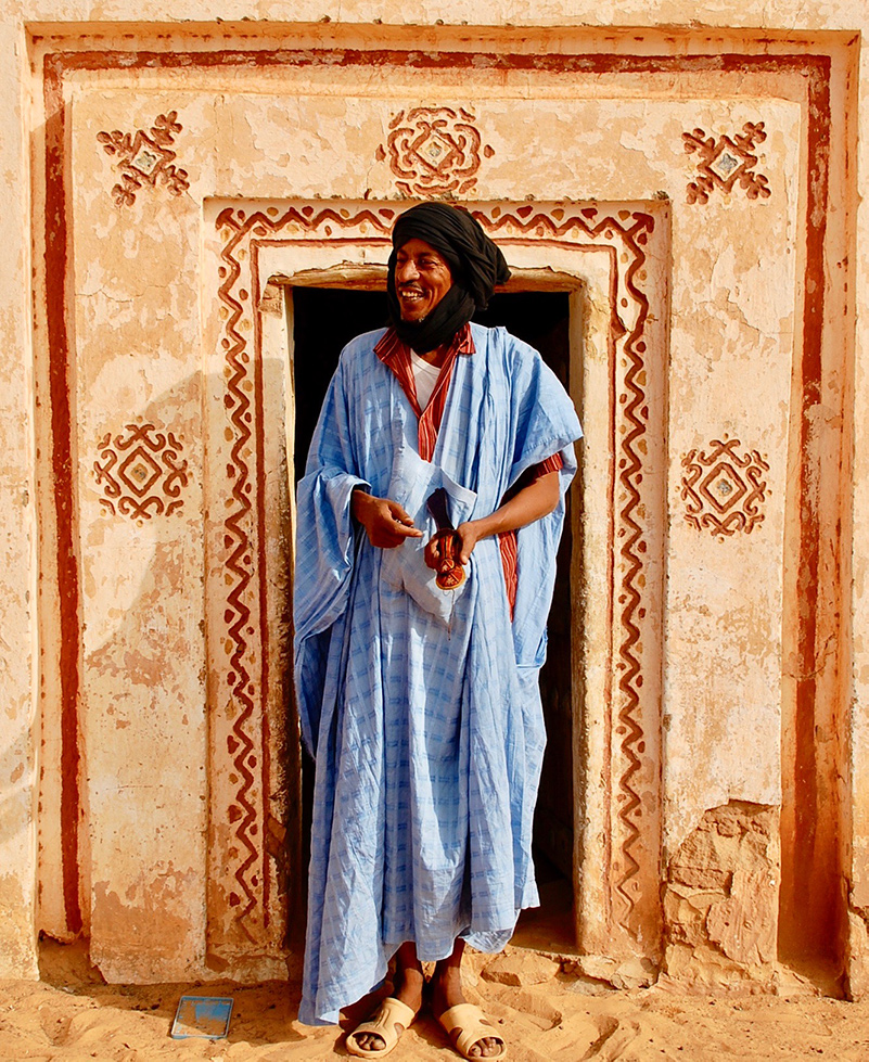 Blue-robed man in front of house in Mauritania