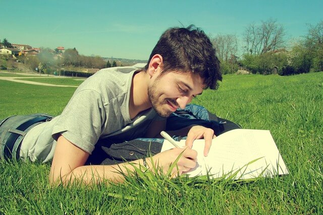 Man travel writing in notebook in a field.