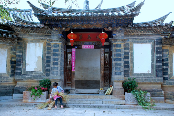 A women with bamboo sitting in front of a temple in China