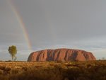 Settling into life in a new country, with rainbow over rocky hill.