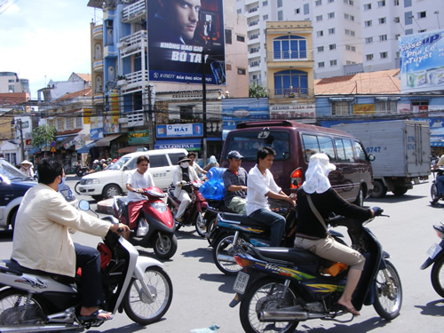 A busy intersection with motorbikes and cars in Ho Chi Minh City.
