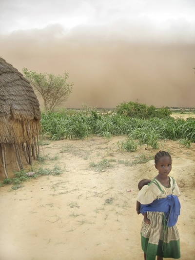 Woman with her baby in fron of her hut in Niger