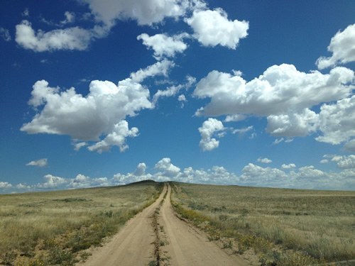 American road trip on a dirt road under the skies.