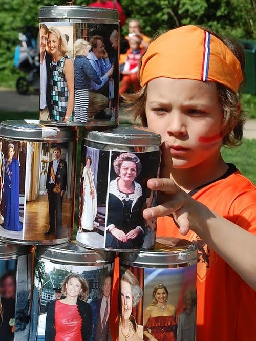 Child  during the Amsterdam festival throwing balls at royal-covered tins.